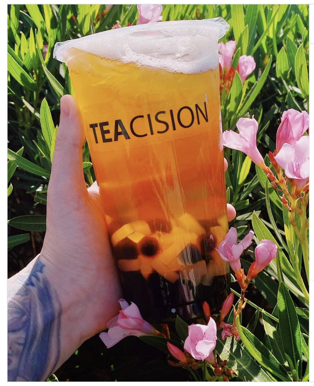 TEACISION fruit tea with boba held in front of pink flowers