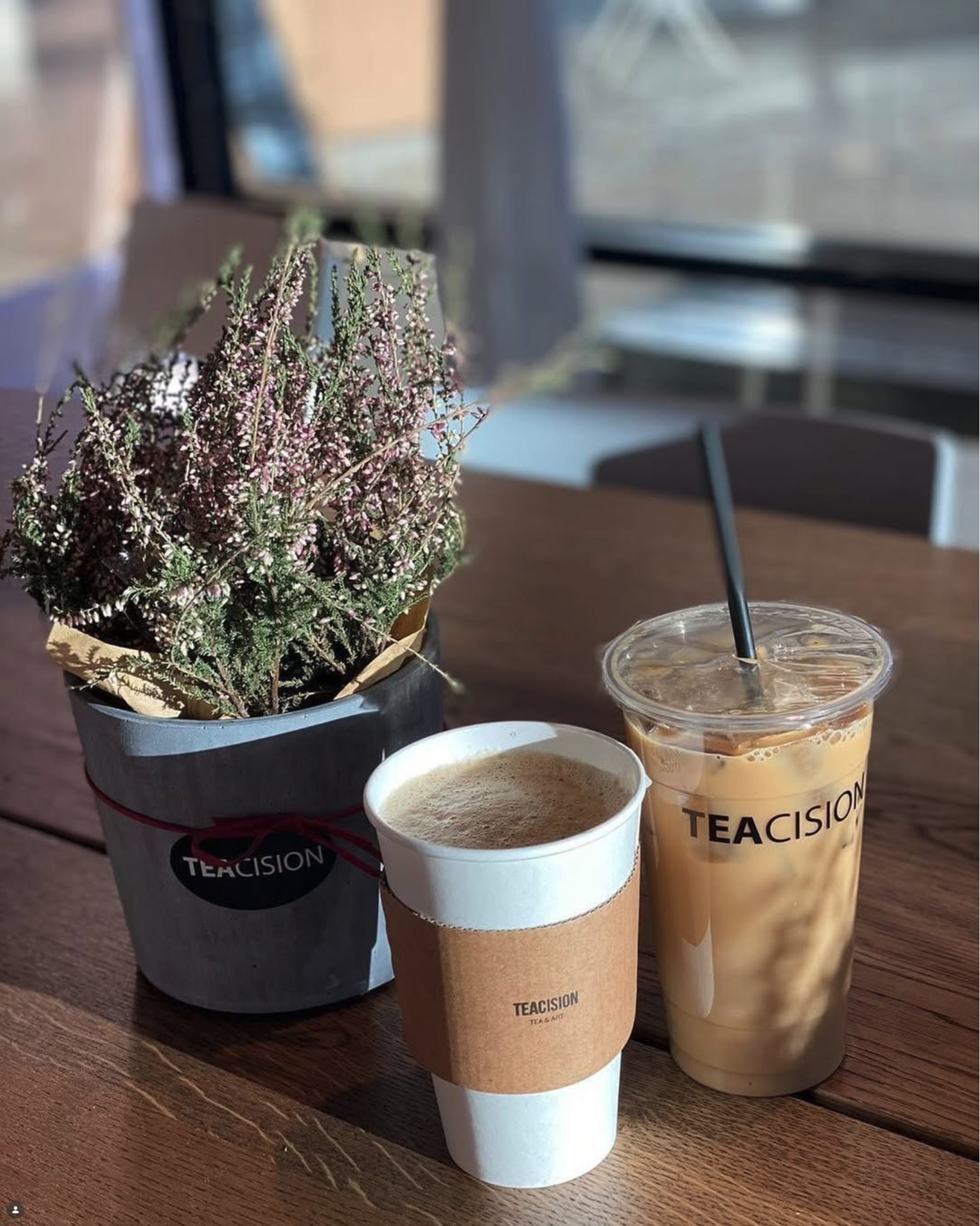 Hot coffee, iced tea, and flowers on a wood table